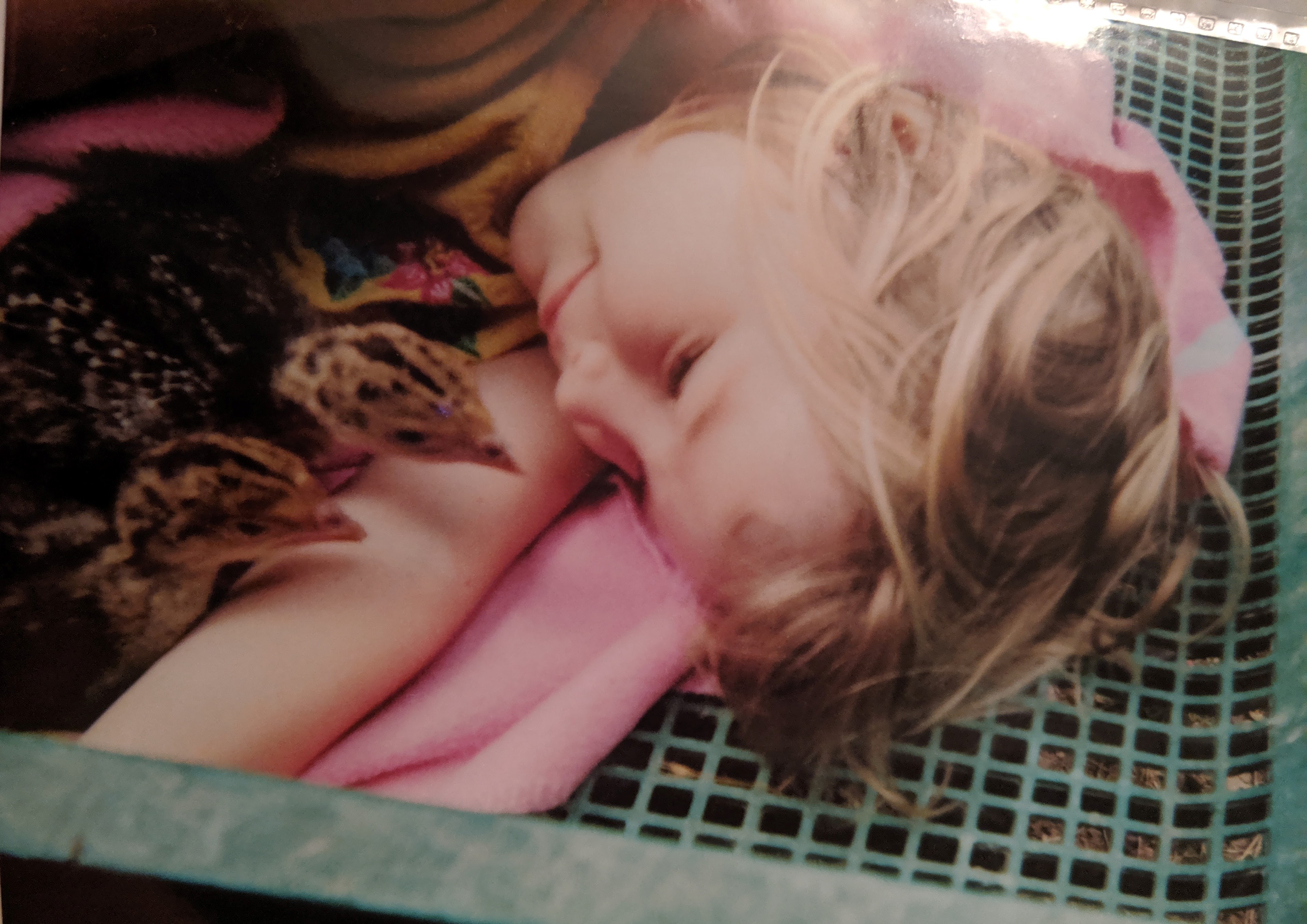 Lily as a child laying on a blanket with baby quails.